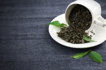 Granulated tea with green leaves in tea-set on grey background