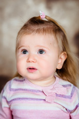 Close-up studio portrait of upset little girl with long blond hair and big grey eyes