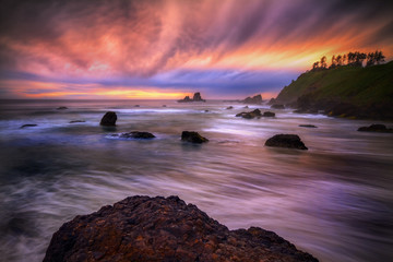 This is a photograph of beach sunset with sea stacks and colorful clouds.
