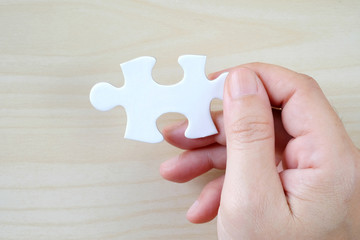 Hand holding a piece of jigsaw puzzle