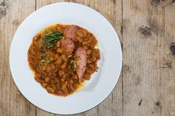 Cassoulet Toulousain from above. French restaurant prepared stew with beans and a variety of pork sausages, served with rosemary
