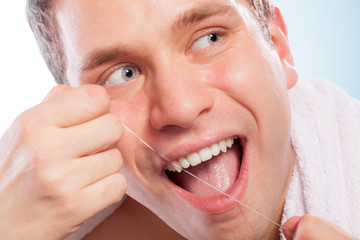 Young man cleaning her white teeth with dental floss