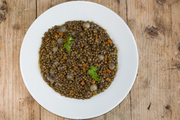 Green lentils with vegetables, on plate from above.French restaurant prepared vegetarian dish with lentils, carrots and mushrooms, served with coriander
