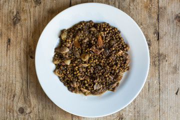 Green lentils with vegetables and bacon, on plate from above. French restaurant prepared dish with lentils, carrots mushrooms and bacon, served with coriander
