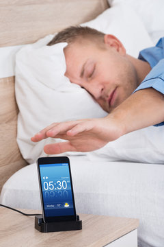 Man Snoozing Alarm On Mobile Phone Screen