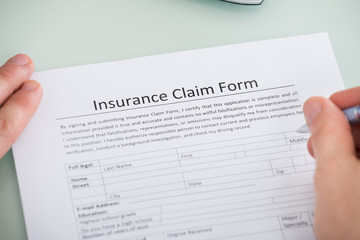 Person Hand Over Insurance Claim Form