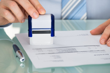 Person's Hand Pressing Stamper On Document