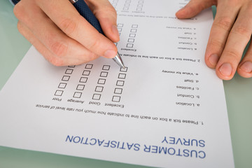 Person Hand Filling Customer Satisfaction Form