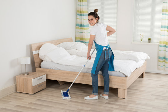 Female Housekeeper Mopping Hardwood Floor