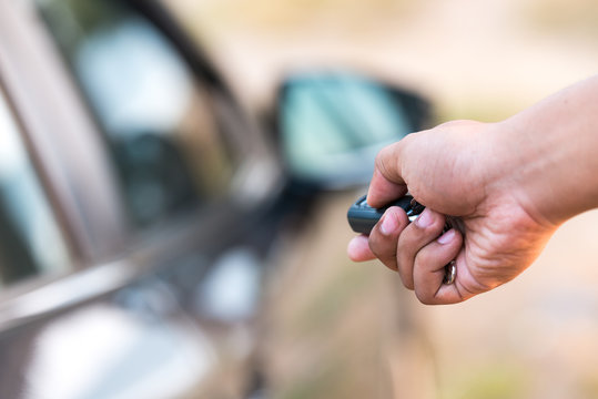 Closeup of a man's hand pushing unlock button on car remote (focus at finger)