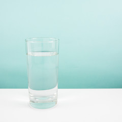 The tall glass of pure mineral water on a white table.
