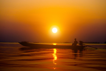 Naklejka na ściany i meble Silhouettes fisherman and sunset on the lake.