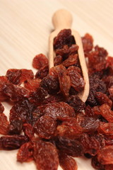 Brown raisins with spoon on wooden table, healthy eating