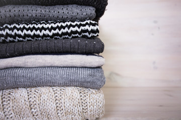 stack of various woolen sweaters on a white wooden background