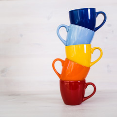 a stack of colorful coffee cups on a white wooden background