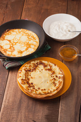 pancakes on a frying pan with sour cream and honey