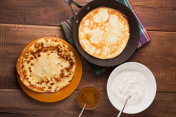 pancakes on a frying pan with sour cream and honey