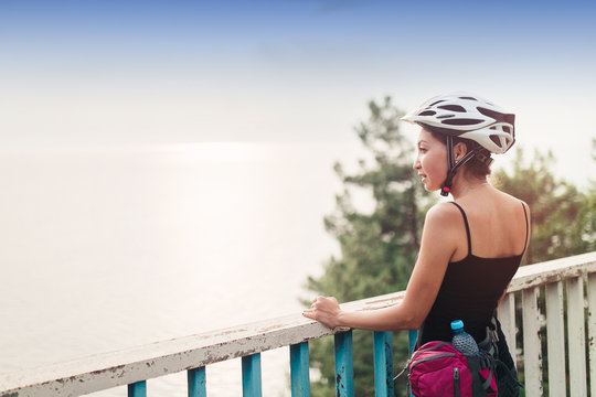 Young tourist woman with helmet standing at the railing of the bridge on the road