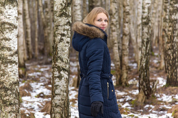Nice, beautiful young lady walking calmly between birch trees in the park