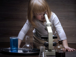A young child and a microscope. Conduct chemical experiments. Chemical vessels. Home Laboratory. Multi-colored fluid