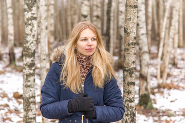 Nice, beautiful young lady walking calmly between birch trees in the park