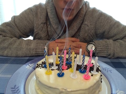 joven soplando las velas del pastel de cumpleaños