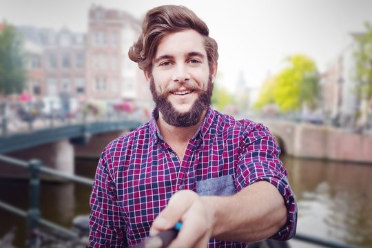 Composite image of portrait of hipster using selfie stick