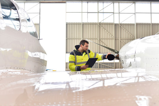 Flugzeugcheck in einem Hangar durch Fachpersonal - Techniker kontrolliert Propeller // Aircraft check in hangar by qualified personnel - technicians controlled propeller of an airplane