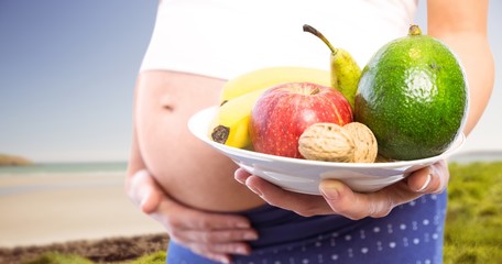 Composite image of pregnant woman showing fruit and veg 