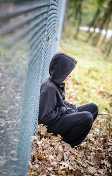 wire fence sitting in front of hooded young