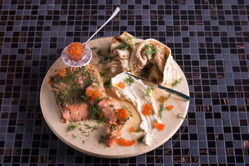 Decorating pancakes with butter and red fish and caviar