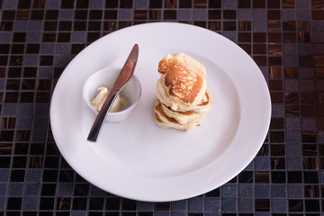 Pancakes with butter on dish with knife