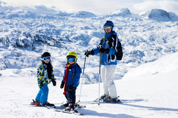 Father and two boys, skiing on a sunny day on a mountain summit