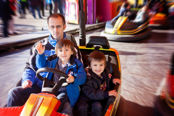 Father and his two sons having a ride in the bumper car at the f