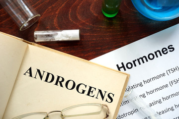 Hormone androgens written on book. Test tubes and hormones list.
