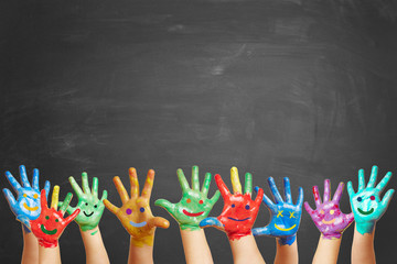 Viele bunt bemalte Kinderhände vor Tafel