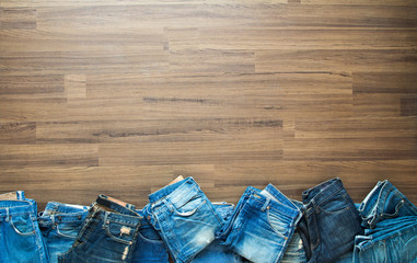 Jeans stacked on a wooden background, View from above 