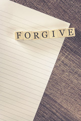 Forgiveness concept. Wooden blocks forming Forgive word on top of a blank letter