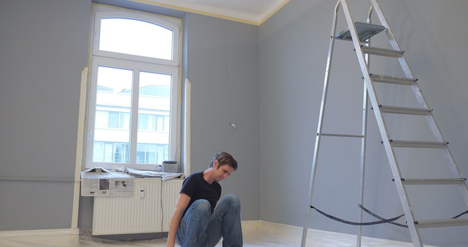 man sitting on floor and shows depressive feelings about the work in his new appartment. then starts working again and feels full of energy.