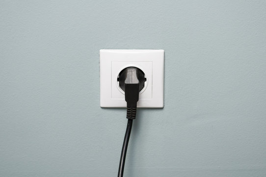 Closeup of electric socket with black cable plugged in
