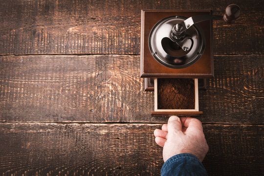 Coffee mill with hand on the wooden table horizontal
