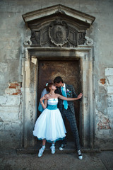 groom is kissing his bride in front of  old door