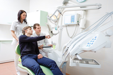 Young man patient at dentist office with doctor and assistant