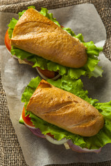 Two delicious sandwiches with vegetable slices, ham and lettuce on napkin, fast food.