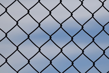 Fototapeta premium Ogrodzenie z siatki drucianej, tło błękitnego nieba