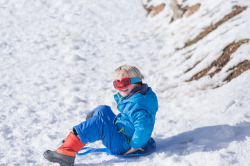 Fototapeta na wymiar Little boy sitting on sled and smiling