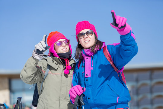 Two women skiers pointing