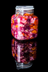 Big glass jar with colourful pickled vegetables on black background with reflection vertical