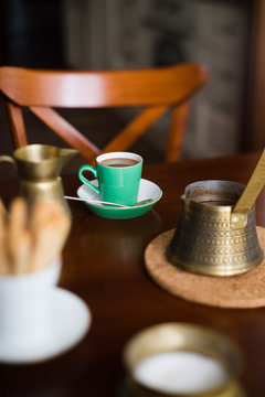 Small cup of coffee surrounded with vintage brass coffee pot, milk jug and sugar can. Tilt-shift and selective focus.