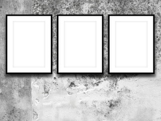 Close-up of three black picture frames on weathered concrete wall background